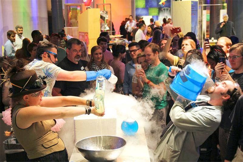 Adults gathered around a hands-on liquid nitrogen science demonstration